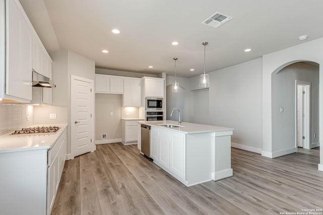 kitchen featuring appliances with stainless steel finishes, tasteful backsplash, white cabinetry, sink, and a center island with sink