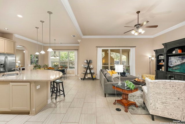 living room with a ceiling fan, arched walkways, and ornamental molding