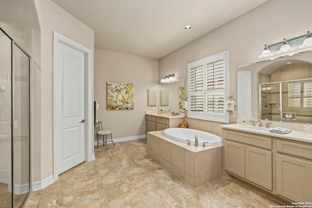 full bath with plenty of natural light, a garden tub, a stall shower, and two vanities