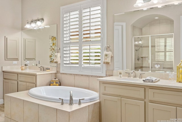 full bath with a sink, a stall shower, a bath, and two vanities