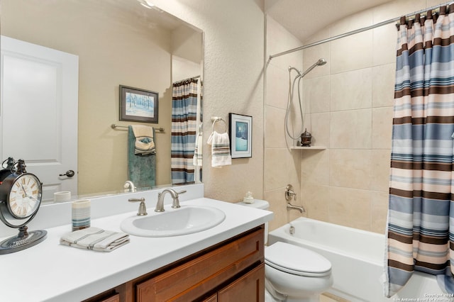 bathroom with vanity, a textured wall, shower / bath combo with shower curtain, and toilet