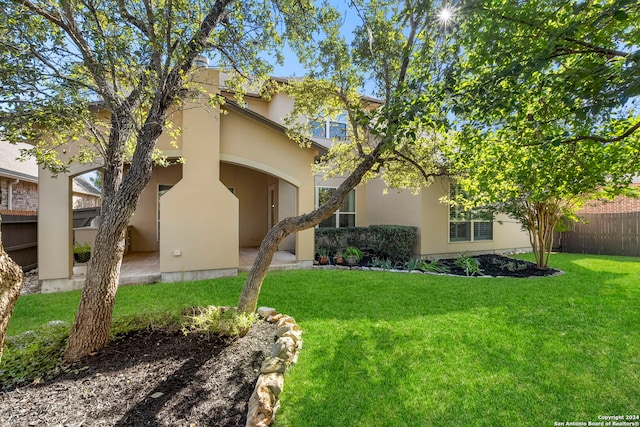view of front of property with stucco siding, a front lawn, and fence