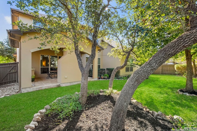 back of property with a lawn, a patio area, stucco siding, and fence