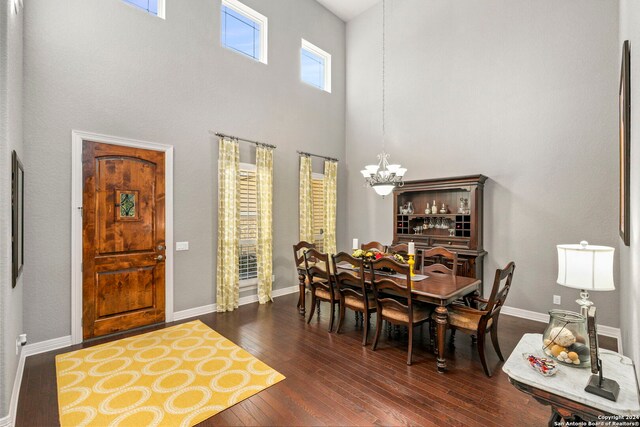 dining space featuring baseboards, a high ceiling, dark wood-style floors, and a chandelier