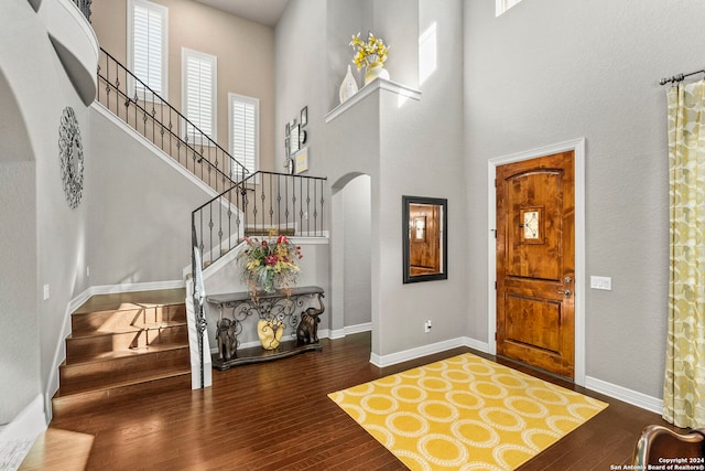 entryway featuring arched walkways, a high ceiling, stairway, and hardwood / wood-style flooring