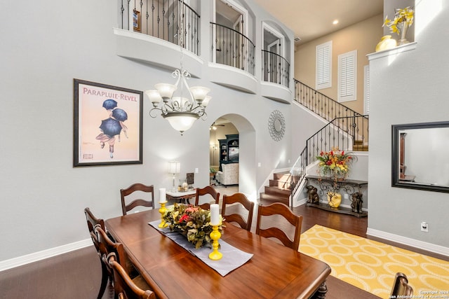 dining room featuring an inviting chandelier, wood-type flooring, and a towering ceiling