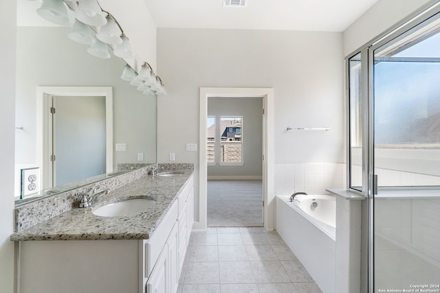 bathroom featuring tile patterned flooring, vanity, a relaxing tiled tub, and a wealth of natural light