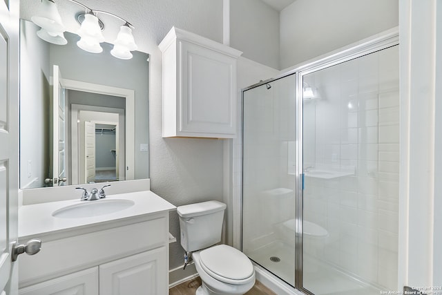 bathroom featuring a shower with door, vanity, and toilet