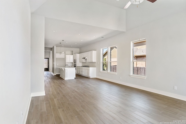 unfurnished living room featuring ceiling fan and hardwood / wood-style floors