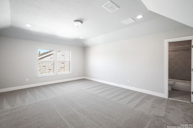 unfurnished bedroom with ensuite bath, lofted ceiling, carpet, and a textured ceiling