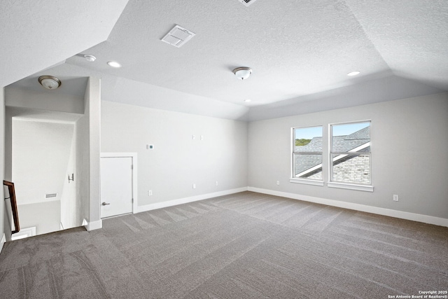 additional living space featuring vaulted ceiling, carpet flooring, and a textured ceiling