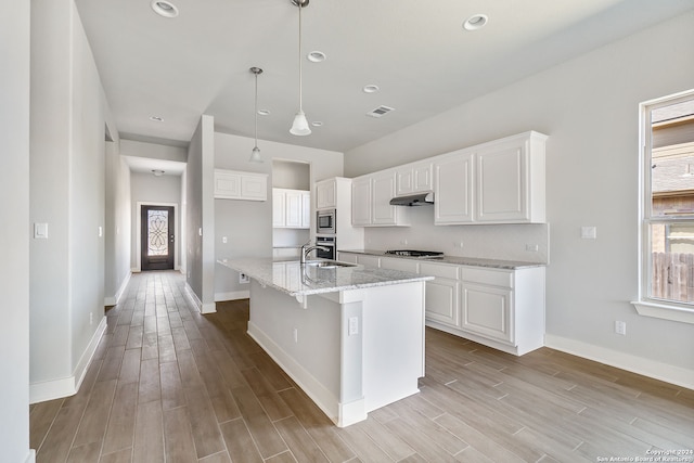 kitchen featuring light wood-type flooring, light stone counters, white cabinetry, and decorative light fixtures