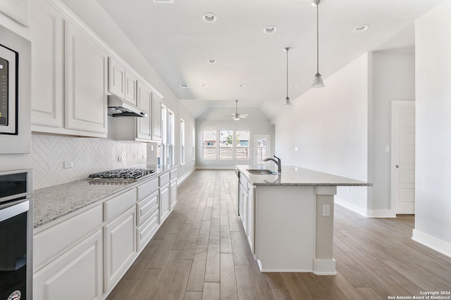 kitchen featuring appliances with stainless steel finishes, hanging light fixtures, white cabinetry, and light hardwood / wood-style flooring