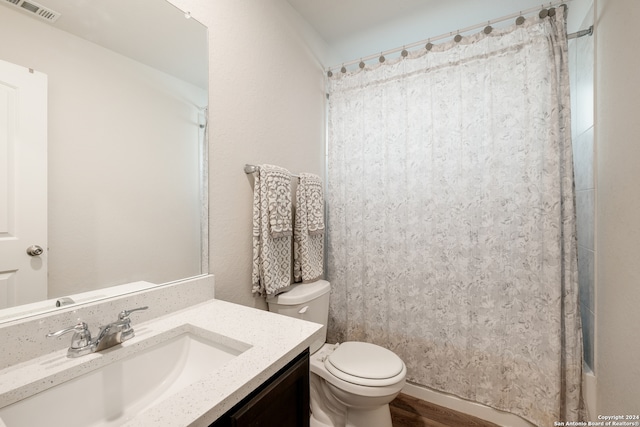 full bathroom featuring hardwood / wood-style flooring, vanity, shower / tub combo, and toilet