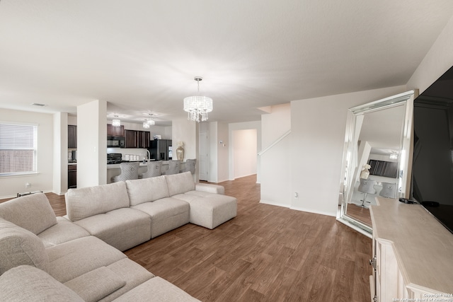 living room with a chandelier, light wood-type flooring, and sink