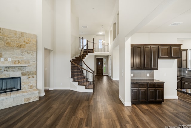 kitchen featuring dark brown cabinets, a stone fireplace, dark hardwood / wood-style floors, and tasteful backsplash