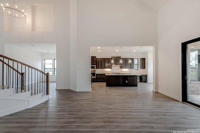 unfurnished living room featuring a high ceiling, a notable chandelier, and dark hardwood / wood-style flooring