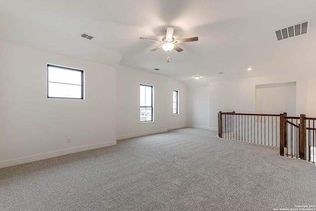 empty room with lofted ceiling, light colored carpet, and ceiling fan