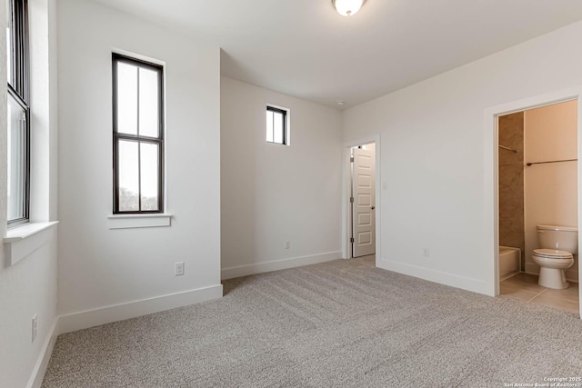 unfurnished bedroom with light carpet and connected bathroom