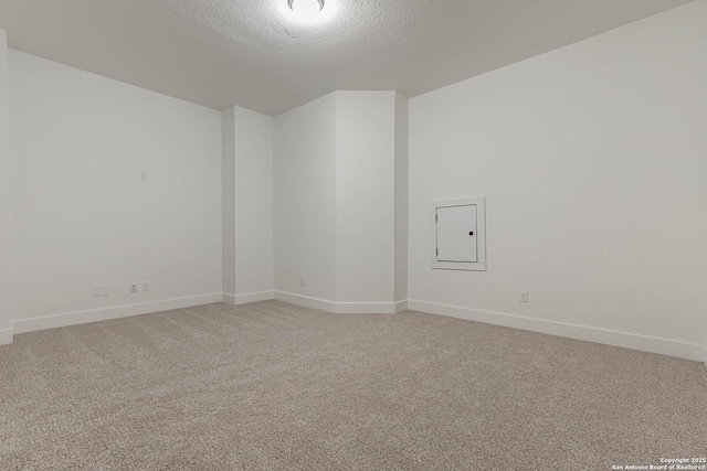 carpeted empty room featuring electric panel and a textured ceiling