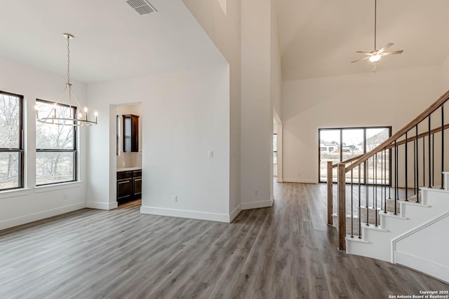 unfurnished living room with ceiling fan with notable chandelier and hardwood / wood-style floors