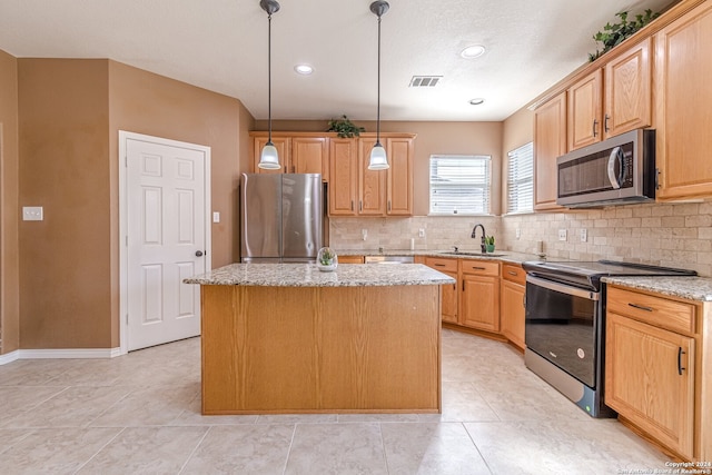 kitchen featuring light stone counters, hanging light fixtures, sink, stainless steel appliances, and a center island