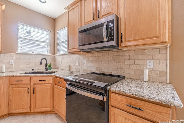 kitchen featuring light stone counters, decorative backsplash, stainless steel appliances, sink, and light tile patterned flooring