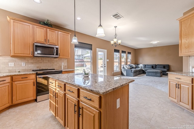 kitchen featuring a kitchen island, light stone counters, hanging light fixtures, appliances with stainless steel finishes, and backsplash