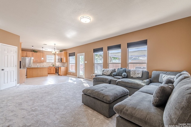 carpeted living room with an inviting chandelier, sink, and a textured ceiling