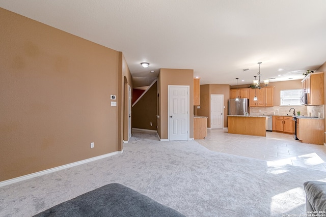 unfurnished living room featuring light colored carpet, a chandelier, and sink