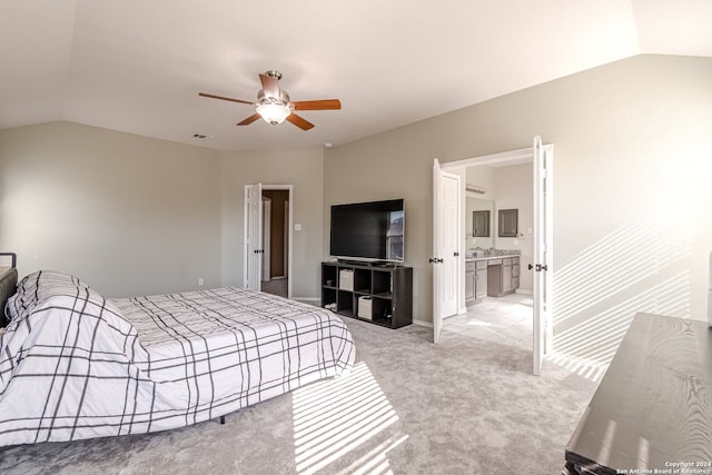 bedroom featuring ceiling fan, light colored carpet, ensuite bathroom, and vaulted ceiling