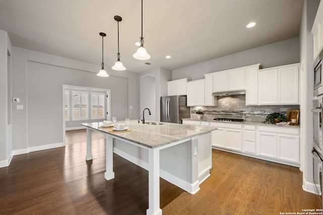 kitchen with hardwood / wood-style floors, stainless steel appliances, white cabinets, sink, and a center island with sink