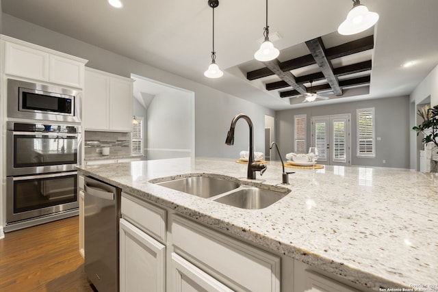 kitchen with light stone counters, white cabinets, sink, appliances with stainless steel finishes, and dark hardwood / wood-style flooring