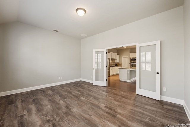 unfurnished living room featuring a wealth of natural light, vaulted ceiling, and dark hardwood / wood-style floors