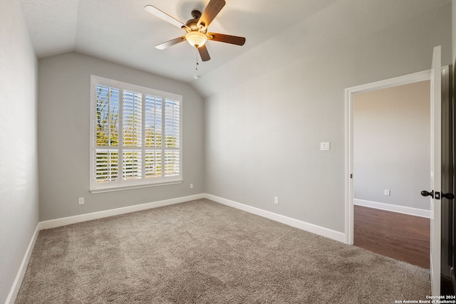 spare room with lofted ceiling, dark carpet, and ceiling fan