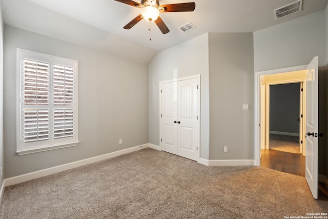 unfurnished bedroom featuring ceiling fan, a closet, vaulted ceiling, and carpet