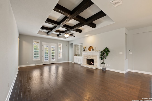 unfurnished living room featuring ceiling fan, coffered ceiling, a stone fireplace, and dark hardwood / wood-style floors