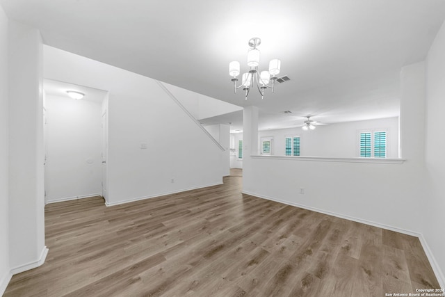 unfurnished living room with ceiling fan with notable chandelier and light wood-type flooring