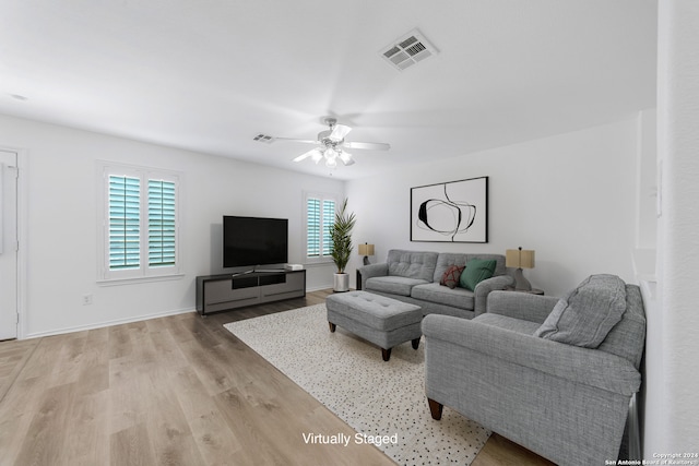 living room featuring ceiling fan, light wood-type flooring, and plenty of natural light