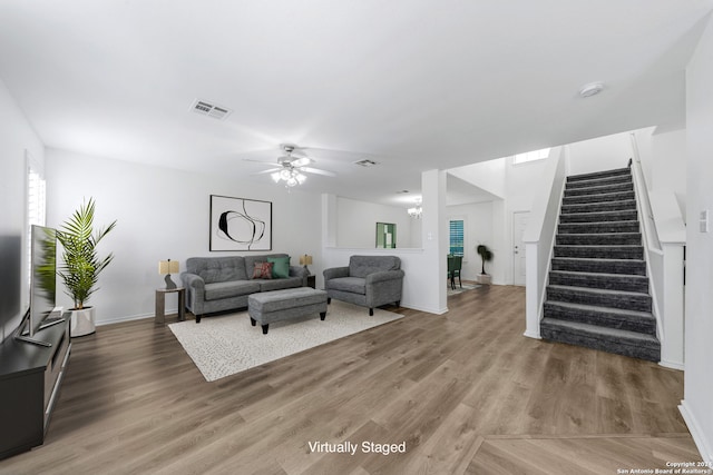 living room with ceiling fan with notable chandelier and hardwood / wood-style floors