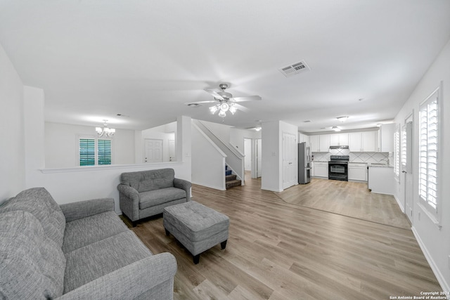 living room featuring ceiling fan with notable chandelier, a wealth of natural light, sink, and light hardwood / wood-style floors