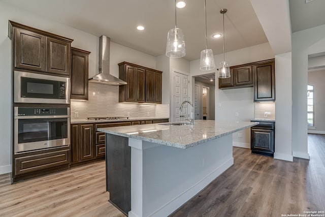 5014 Estates Oak Way, San Antonio, TX 78263 - kitchen featuring stainless steel appliances, wall chimney range hood, a sink, light wood finished floors, and recessed lighting