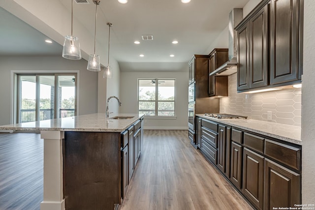 5014 Estates Oak Way, San Antonio, TX 78263 - kitchen with a sink, a ceiling fan, light wood-style flooring, an island with sink, and dark brown cabinetry