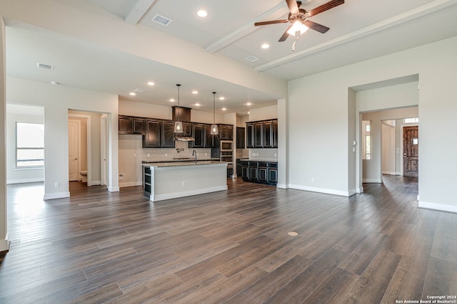 unfurnished living room featuring beam ceiling, sink, dark wood-type flooring, and ceiling fan