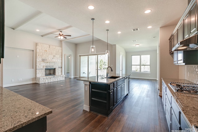 kitchen featuring sink, dark hardwood / wood-style flooring, hanging light fixtures, stainless steel appliances, and a kitchen island with sink