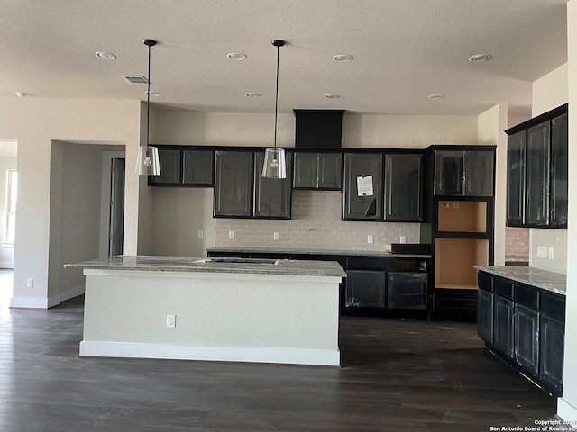 kitchen featuring dark wood-type flooring, decorative backsplash, pendant lighting, and a kitchen island