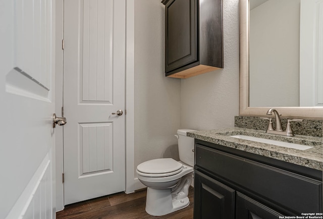 bathroom with toilet, vanity, and wood-type flooring