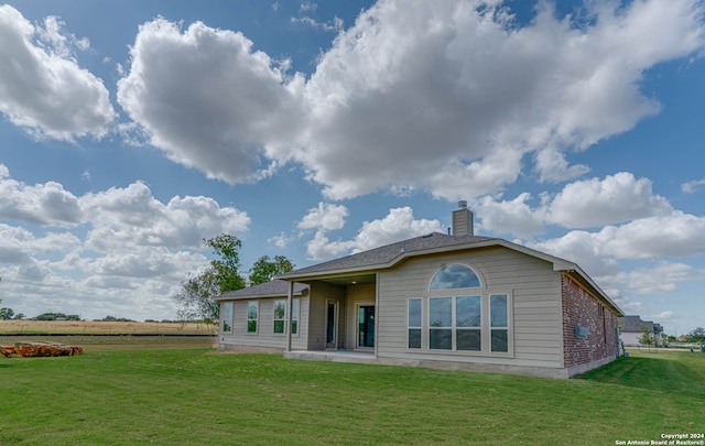 rear view of house featuring a patio area and a yard