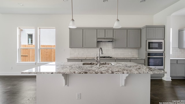 kitchen with hanging light fixtures, gray cabinets, stainless steel oven, and built in microwave