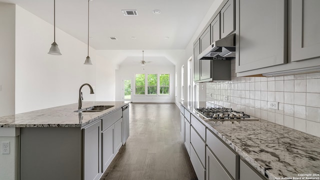 kitchen with gray cabinetry, a kitchen island with sink, light stone counters, and sink